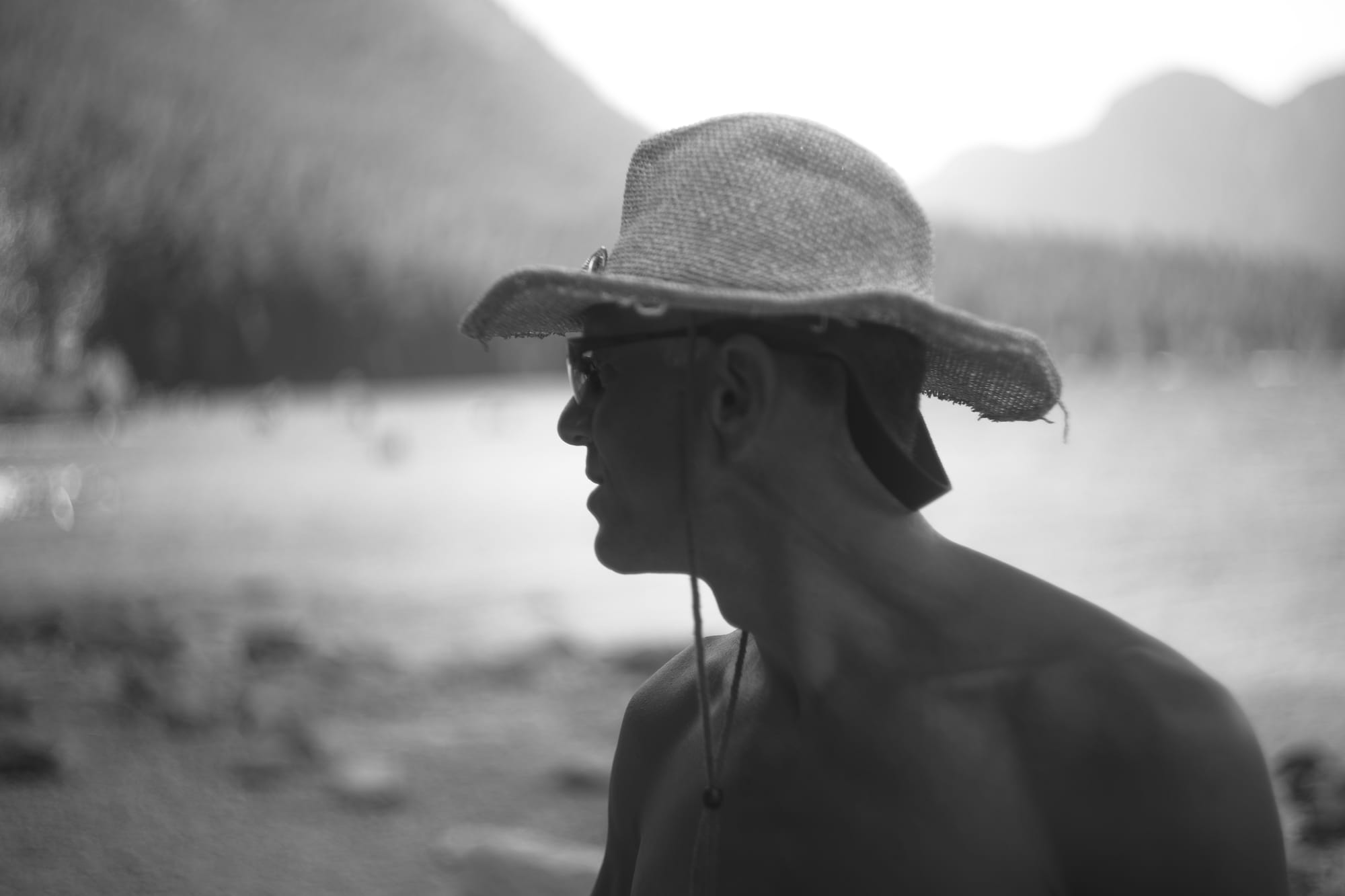 A photograph of a man's profile. He's wearing a straw hat and sunglasses.