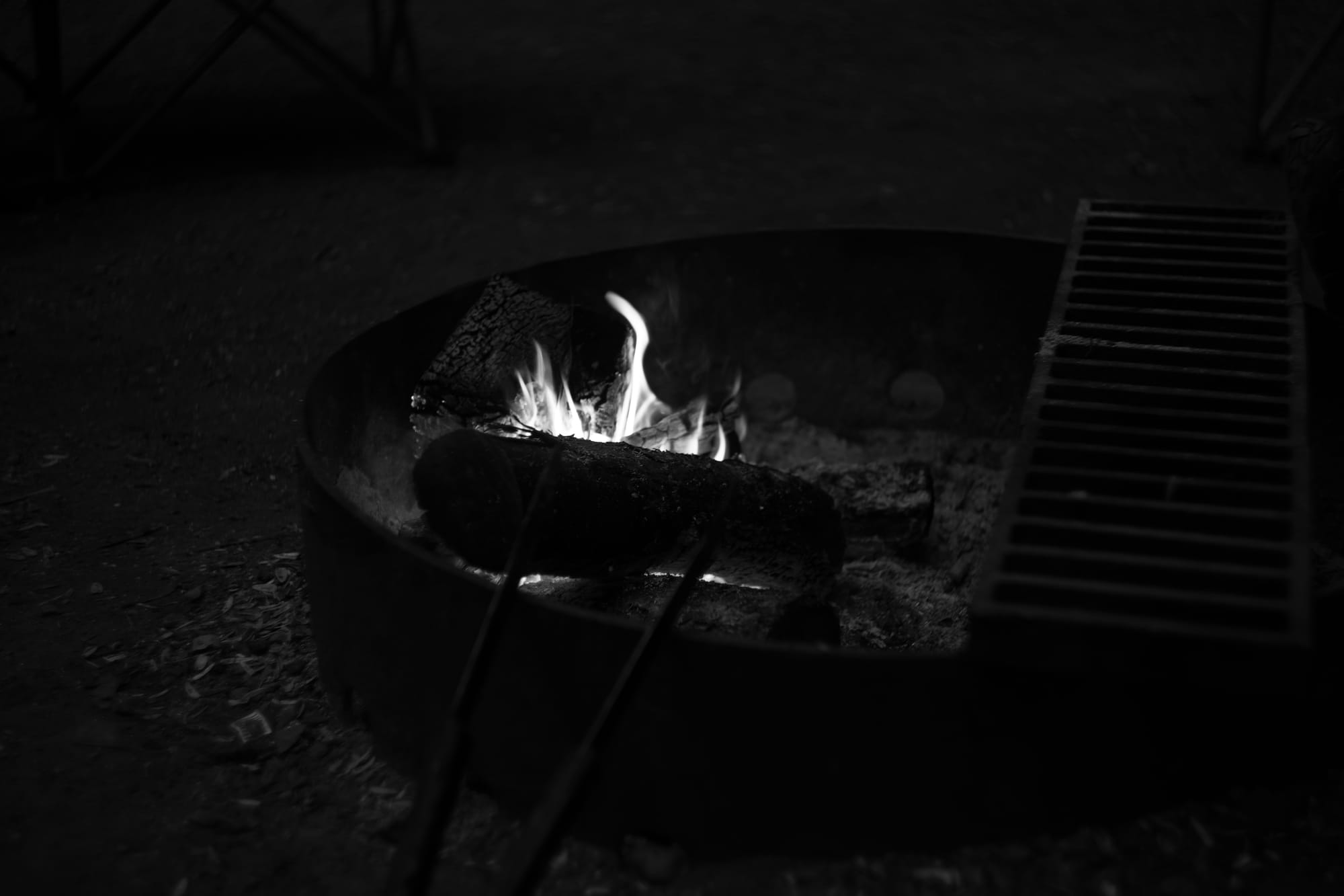 A black and white photograph of a fire pit with flames shooting up